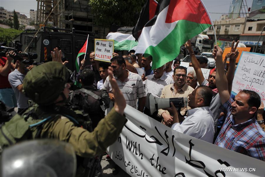 Palestinians carry national flags and banners as they take part in a rally to mark the 49th anniversary of "Naksa Day", commemorating the displacement of Palestinians that occurred after Israel