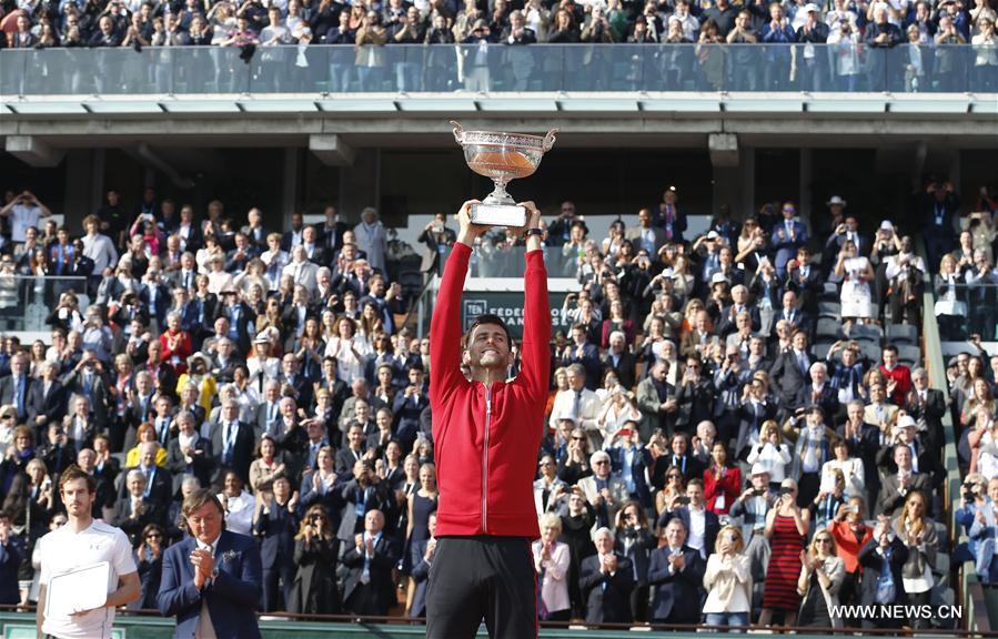 Novak Djokovic of Serbia lifts the champion trophy during the awarding ceremony for the men