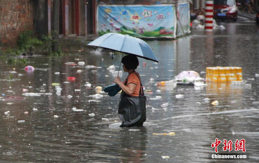 Photo taken on June 14, 2016 shows a resident wade through waterlogged Liguo Road in Liujiang County of Liuzhou, south China