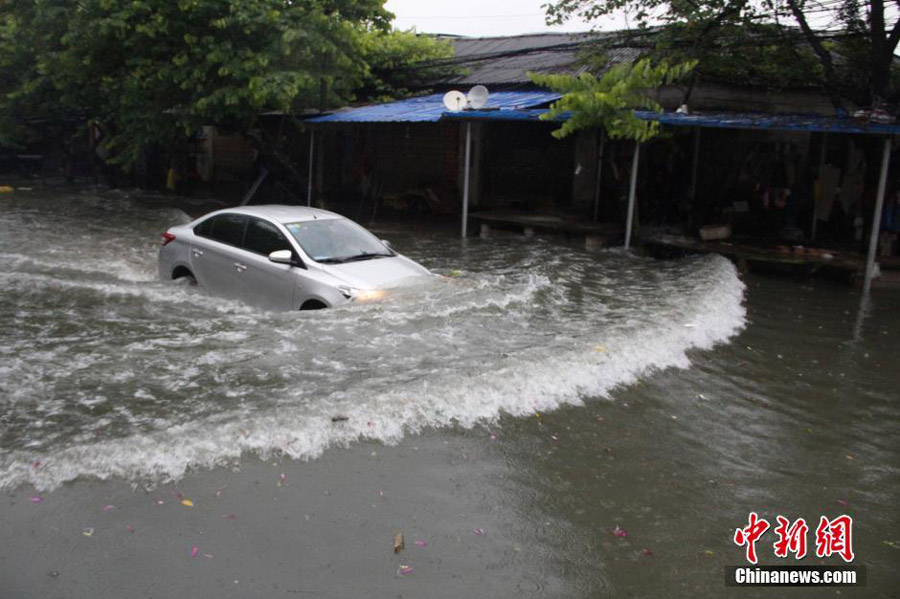 Photo taken on June 14, 2016 shows a car struggling to drive through waterlogged Liguo Road in Liujiang County of Liuzhou, south China