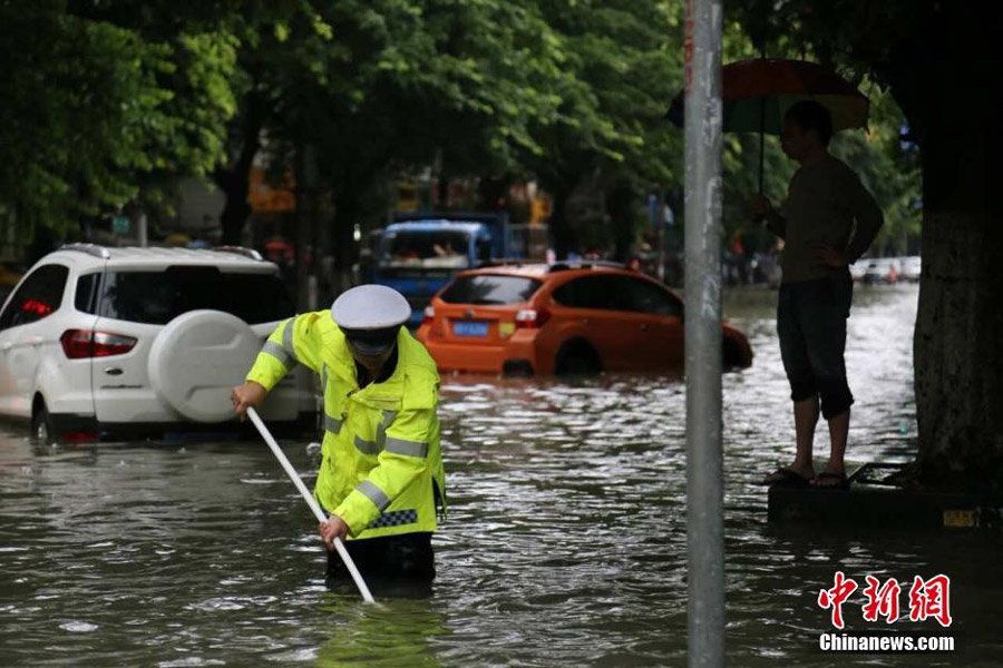 Photo taken on June 14, 2016 shows a traffic police officer standing in waterlogged Liguo Road in Liujiang County of Liuzhou, south China