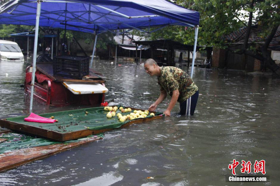 Photo taken on June 14, 2016 shows a fruit vendor standing in waterlogged Liguo Road in Liujiang County of Liuzhou, south China