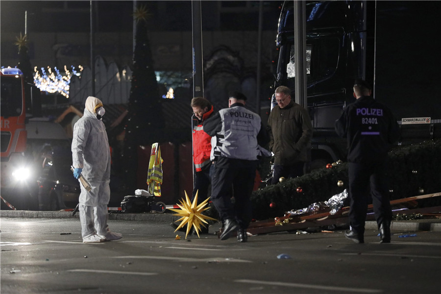 A specialist in a protective suit looks at police walking walk past a truck at a Christmas market in Berlin, Germany, December 19, 2016 after a truck ploughed into the crowded Christmas market in the German capital. 