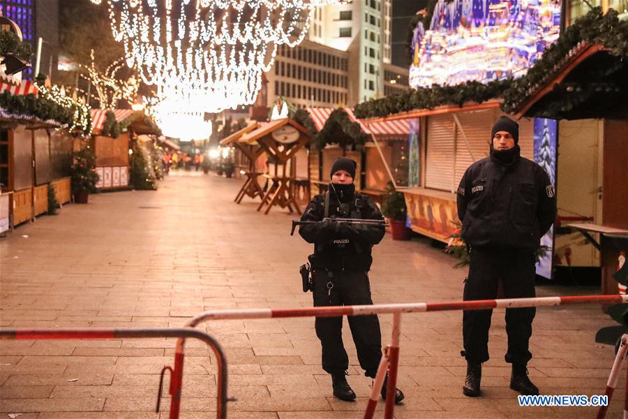 Police officers stand guard near the attacked Christmas market in Berlin, capital of Germany, on Dec. 21, 2016. German police is searching nationwide for a 23-year-old man under suspect after a lorry ploughed into a crowd at a Christmas market in Berlin on Monday night, killing 12 people and injuring many others. (Xinhua/Shan Yuqi) 