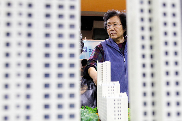 A visitor examines a property project model at a real estate expo in Beijing. [Photo/China Daily]