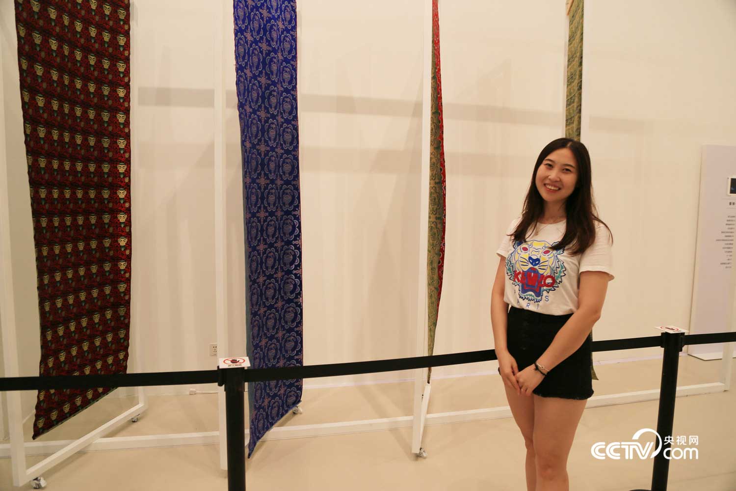 Exhibition visior Ms. Sun poses with Sichuan brocade cloths
