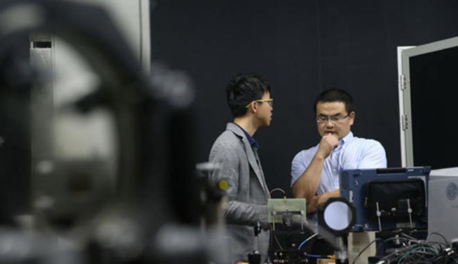 冷用斌（右）在上海光源同步光诊断实验室内与科研团队的一名同事商讨实验方案（5月27日摄）。新华社记者 裴鑫 摄