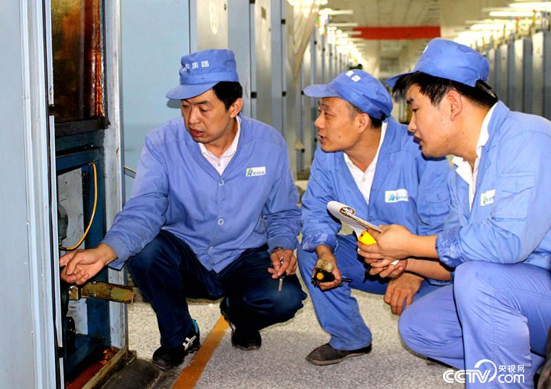 李强（左一）和同事正在检修设备。