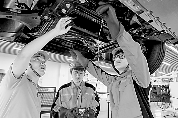 安徽省芜湖机械工程学校实训基地,学生在老师的指导下学习新能源汽车维修。肖本祥摄/光明图片