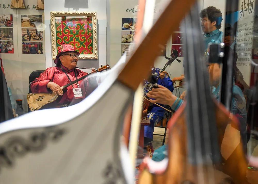 在新疆美术馆展馆内，来自新疆博尔塔拉蒙古自治州的非遗传承人在现场演奏民族乐器。