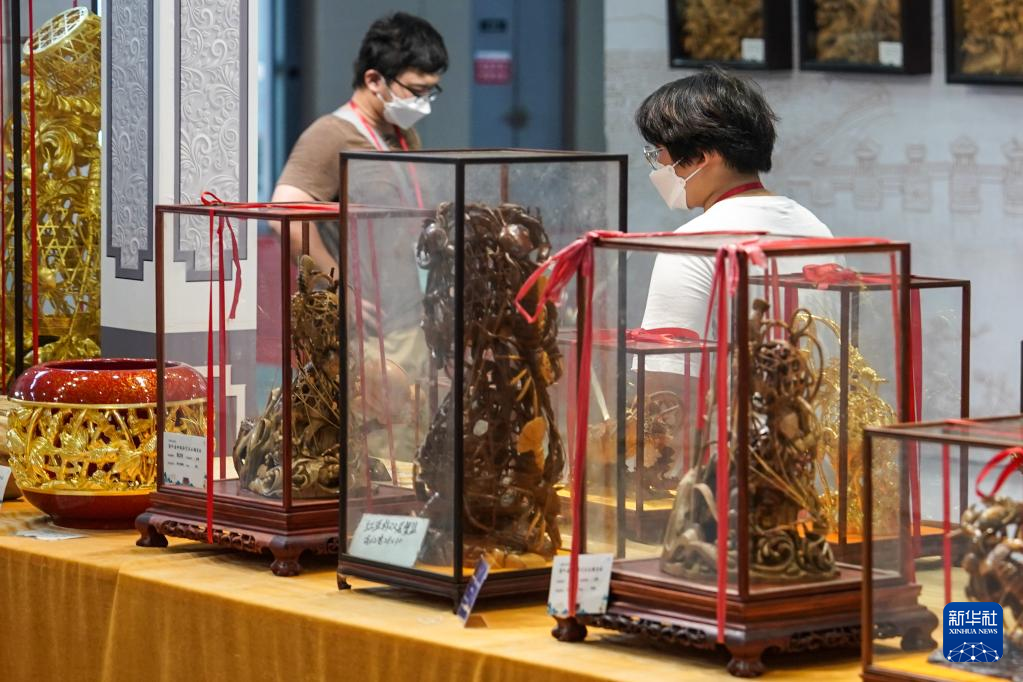 8月18日，观众在第二届中国工艺美术博览会参观木雕艺术展品。