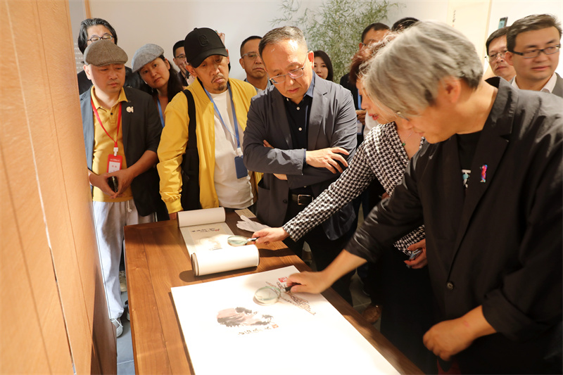 嘉宾用放大镜观赏齐白石的工虫画册（复制品）