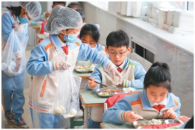 首都师范大学附属小学某班级分餐员分发馒头。