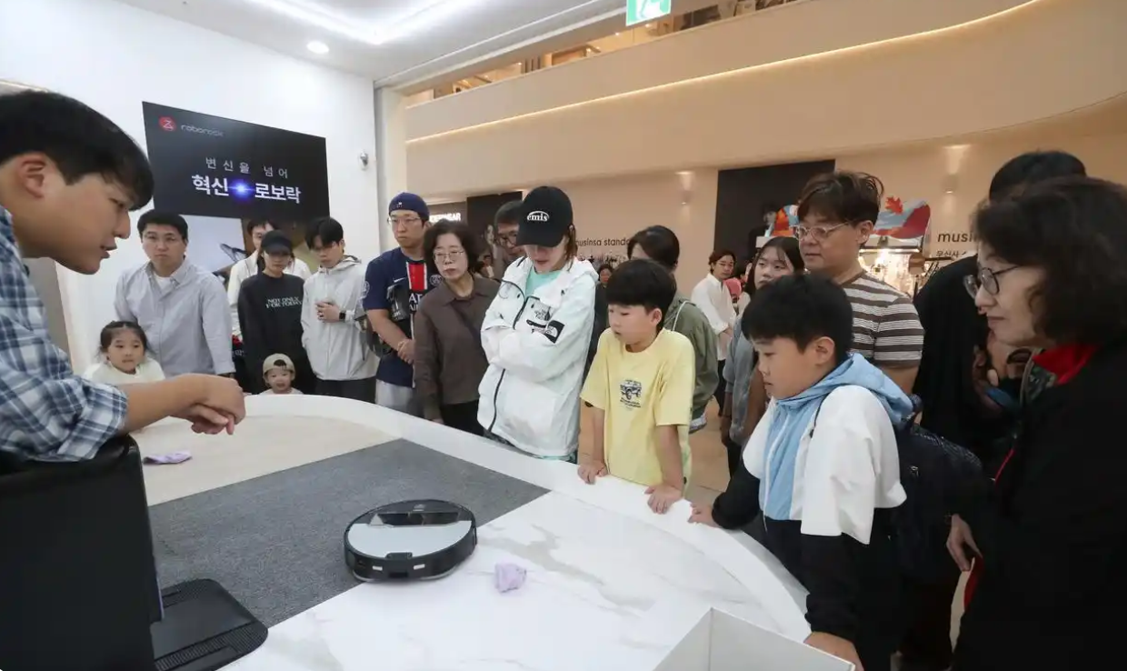 2025年10月12日，在韩国首尔近郊的一家大型购物中心，韩国消费者观看中国品牌扫地机器人演示。新华社记者 姚琪琳 摄
